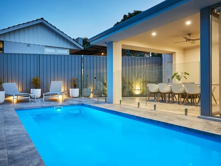 Imperial Series fibreglass pool lit at dusk beside a modern home